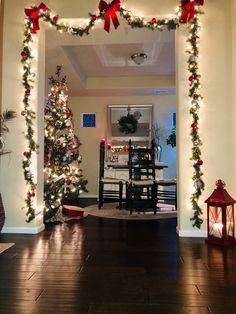 a christmas tree is decorated with red bows and lights in front of a dining room table