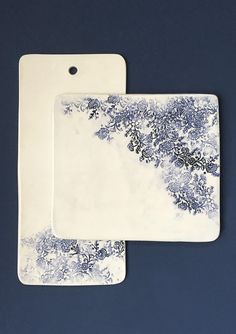 two white and blue serving trays with designs on the sides, one is holding a plate