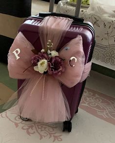 a purple piece of luggage with a pink bow and flowers on the handle is shown