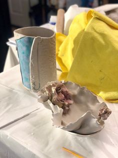 two vases sitting on top of a table covered in yellow and white cloth next to each other