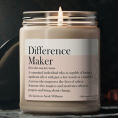 a candle that is sitting on a table next to a jar with the words difference maker written on it