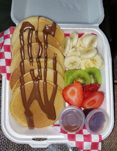 a lunch box filled with fruit and chocolate covered waffles, bananas, strawberries, and kiwi slices