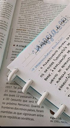 an open book sitting on top of a table next to a pen and paper clip