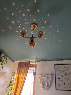 a ceiling with stars painted on it and lights hanging from the ceiling, in front of a window