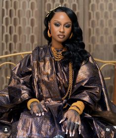 a woman sitting on top of a bed wearing a gold dress