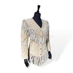 Elevate your Western-inspired wardrobe with this stunning Women's Beige Suede Leather Fringe Jacket, a perfect blend of rustic cowboy charm and Native American style. This jacket is meticulously crafted from high-quality, genuine suede leather, offering a soft yet durable feel that gets better with age. The standout feature is the long fringe detailing, which cascades along the sleeves, front, and back, giving it an iconic Western look that is both playful and sophisticated. The jacket's neutral beige color makes it versatile, easy to pair with a variety of outfits, from casual jeans and boots to more dressed-up occasions. Its timeless design draws inspiration from both classic cowboy styles and Native American artistry, combining traditional elements like fringes, a pointed yoke, and fron Western Style Fitted Leather Jacket For Fall, Western Style Fitted Leather Jacket For Winter, Fitted Western Leather Jacket For Winter, Western Style Long Sleeve Outerwear For Western-themed Events, Bohemian Fitted Leather Jacket For Fall, Fitted Western Leather Jacket With Long Sleeves, Fitted Western Outerwear For Rodeo, Style Mantel, Leather Fringe Jacket