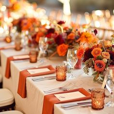 the table is set with orange and red flowers