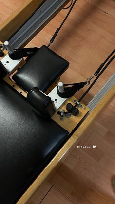 a black leather chair with metal legs and straps on the backrest, in front of a wooden floor