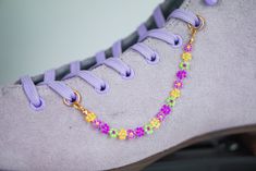 Purple, yellow and neon green beaded Daisy Chain Lacelet. Alternating matte Purple, luminous purple, neon green and sunshine yellow beaded daisies with a gold finish. Handmade with seed beads.  Can be mixed, matched and styled with other accessories. Add them onto skates, shoes, boots, sneakers, etc. If you would like a matching pair, please add two to your cart :) ⚡️Listing is for ONE lacelet, skates, boots or other accessories pictured NOT included⚡️ These two have very slight variations betwe Beaded Daisy Chain, Roller Skate Accessories, Lace Charms, Shoe Chain, Skate Accessories, Skates Shoes, Beaded Daisy, Beaded Shoes, Lace Accessories