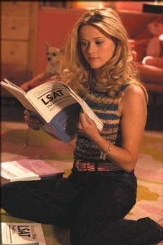 a woman sitting on the floor reading a book