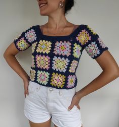 a woman wearing white shorts and a crocheted top with colorful flowers on it