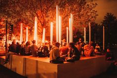 a group of people sitting on top of a cement block next to each other at night