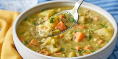 a spoon full of soup with carrots and potatoes