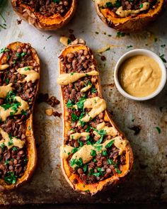 baked stuffed butternut squash on a baking sheet with some dipping sauce in the middle