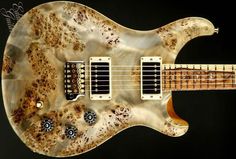 an electric guitar that has been made out of wood and marbled with black spots