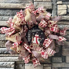 a christmas wreath on the side of a brick wall with red and white ribbon around it