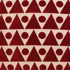 a red and white rug with triangle shapes on the bottom, in front of an off - white background