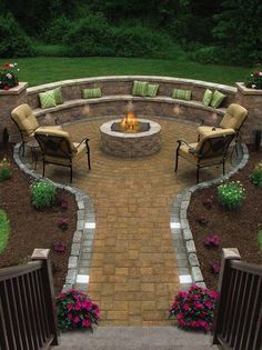 an outdoor fire pit surrounded by chairs and flowers