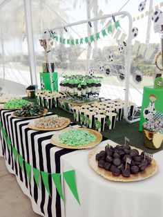 a table topped with lots of green and black desserts next to a tented area