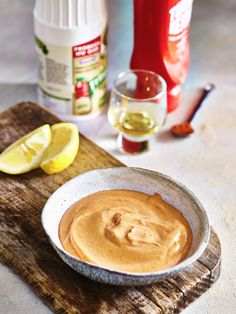 a bowl of peanut butter sits on a cutting board next to some lemons and other ingredients