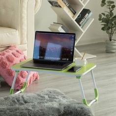 a laptop computer sitting on top of a table next to a white chair in a living room