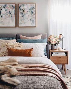 a bedroom with two paintings above the bed