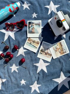 an old polaroid camera, sunglasses and cherries on a blue blanket with white stars