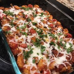 a casserole dish with tomatoes, cheese and parsley on top in a glass pan