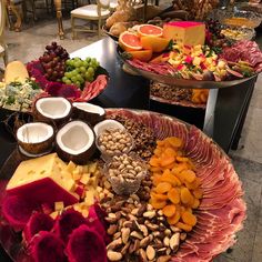 an assortment of fruits, nuts and cheeses displayed on two platters in a restaurant