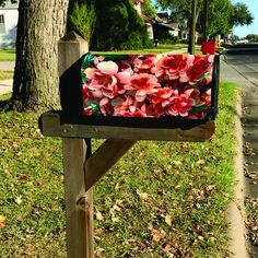 a mailbox with flowers in it sitting on the side of a road next to a tree