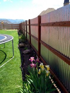 a fenced in yard with flowers and a table on the grass next to it