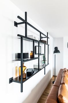 a leather couch sitting in front of a wall mounted shelf filled with books and vases