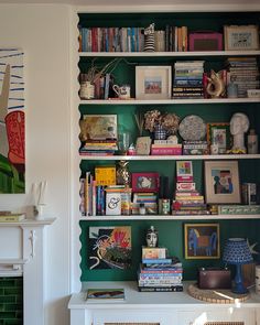 a bookshelf filled with lots of books next to a fireplace