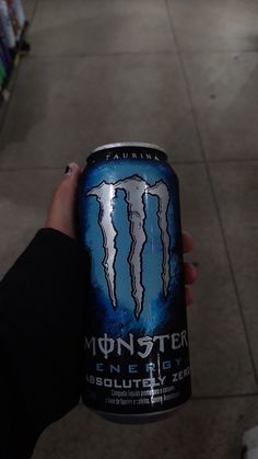 a person holding up a can of monster energy