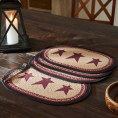 two placemats with red stars are sitting on a table next to a candle