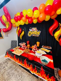 a table topped with lots of food next to a bunch of red and yellow balloons