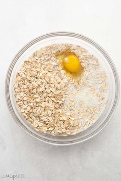 oatmeal and an egg in a glass bowl on a white table top