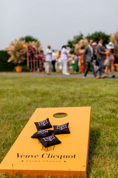 a yellow cornhole board with black pillows on it sitting in the middle of a grassy field