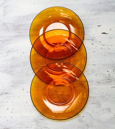 two orange plates sitting on top of a white table next to each other with yellow rims