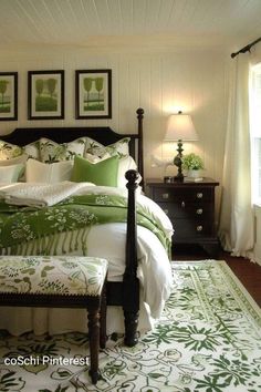 a bedroom with green and white bedding, pictures on the wall and rugs