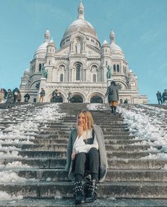 a woman sitting on the steps in front of a building with snow all around her