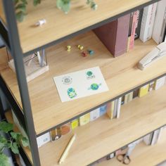 a book shelf with some books on top of it next to a potted plant