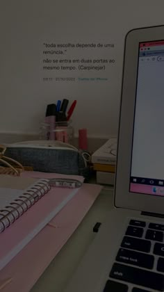 an open laptop computer sitting on top of a desk next to a notepad and pen