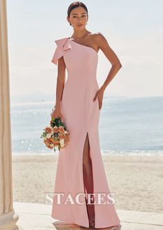 a woman in a pink dress standing on the beach