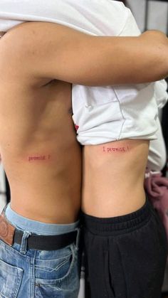 two people with small tattoos on their butts, one is holding the other's back