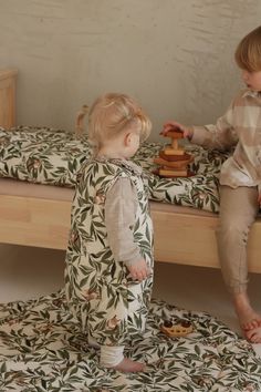 two toddlers playing with toys on a bed