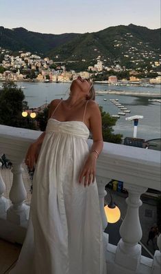 a woman in a white dress standing on a balcony