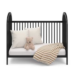 a teddy bear sitting on top of a bed next to two white pillows and a striped blanket