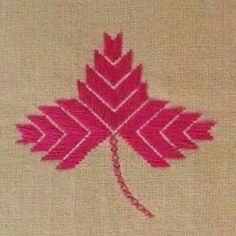 a red leaf is embroidered on the side of a piece of fabric with pink thread