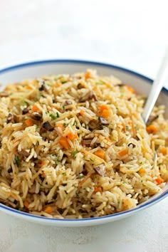 a bowl filled with rice and carrots on top of a table